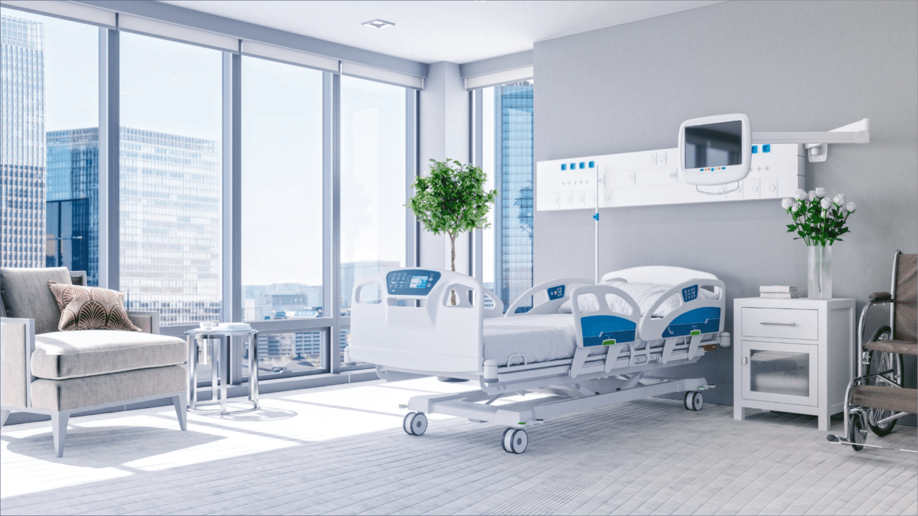 patient-room-clinic-environmentwebp - Sentrax Hospital room with large windows overlooking a city skyline, featuring an adjustable bed, wall monitor, IV pole, and bedside table with flowers.